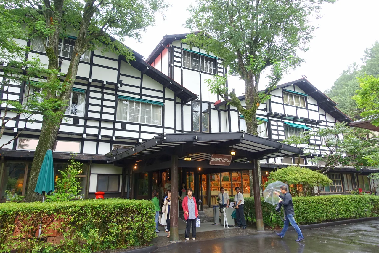 A timber hotel building with a tiled roof seen from the drive