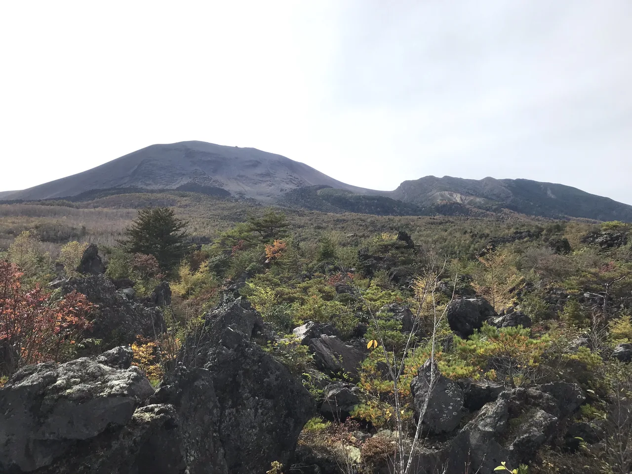 A field of broken black rock with a bare volcano rising behind it