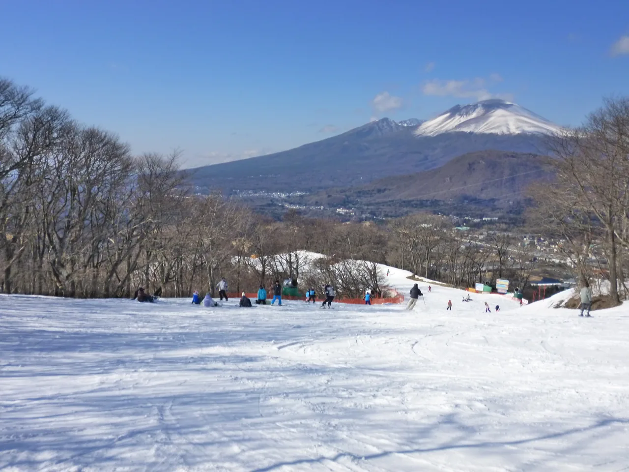 A snow-covered slope with a volcano rising behind it