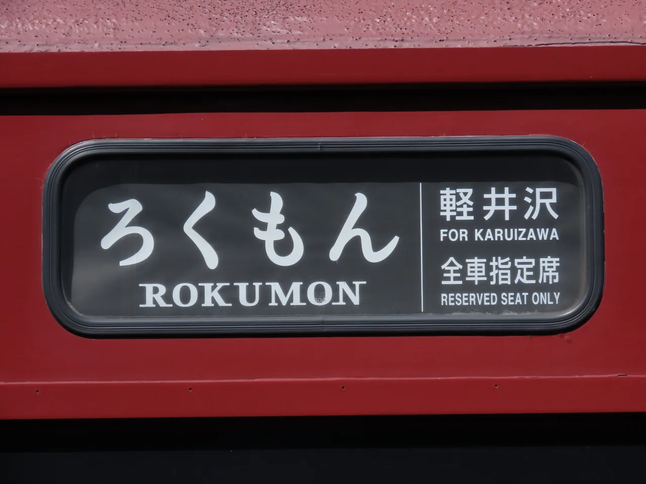 A red train side panel carrying the word Rokumon and the name Karuizawa
