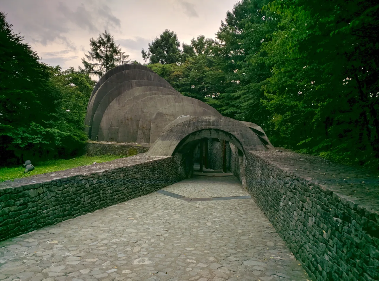 Curved arches of stone and glass set low into a grassy slope