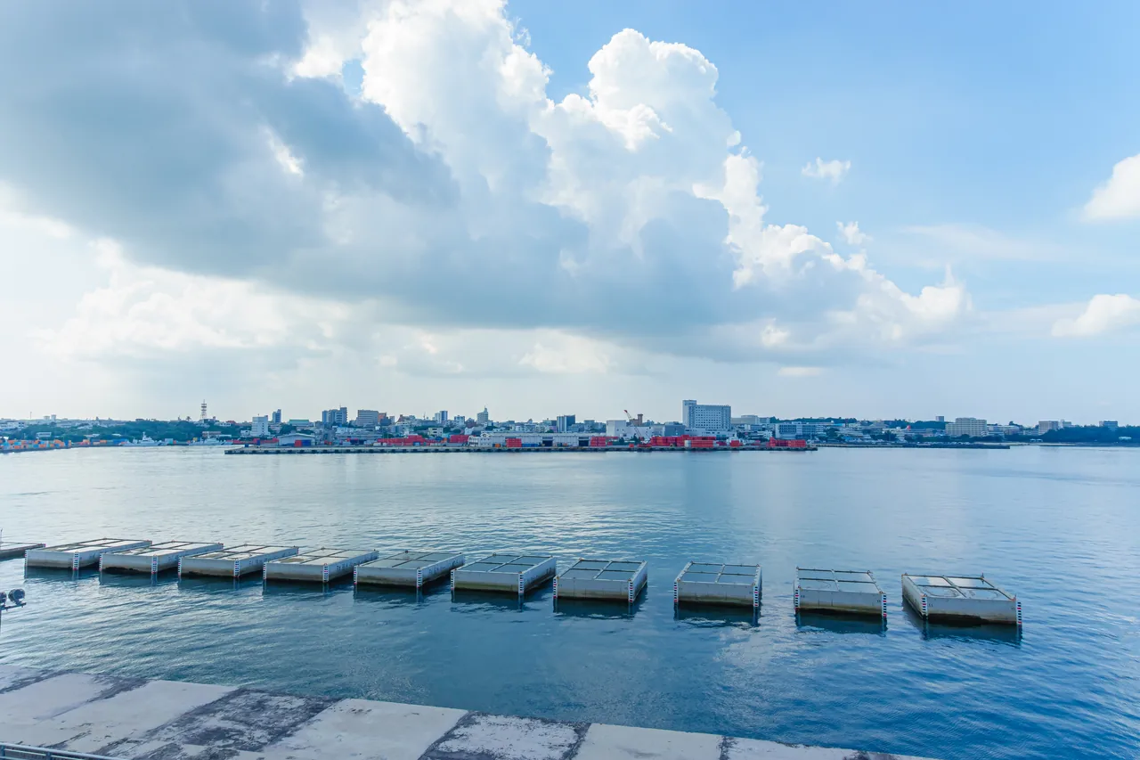 Hirara Port on Miyakojima in the morning, with the breakwater in front and the low skyline of the island's only town behind it