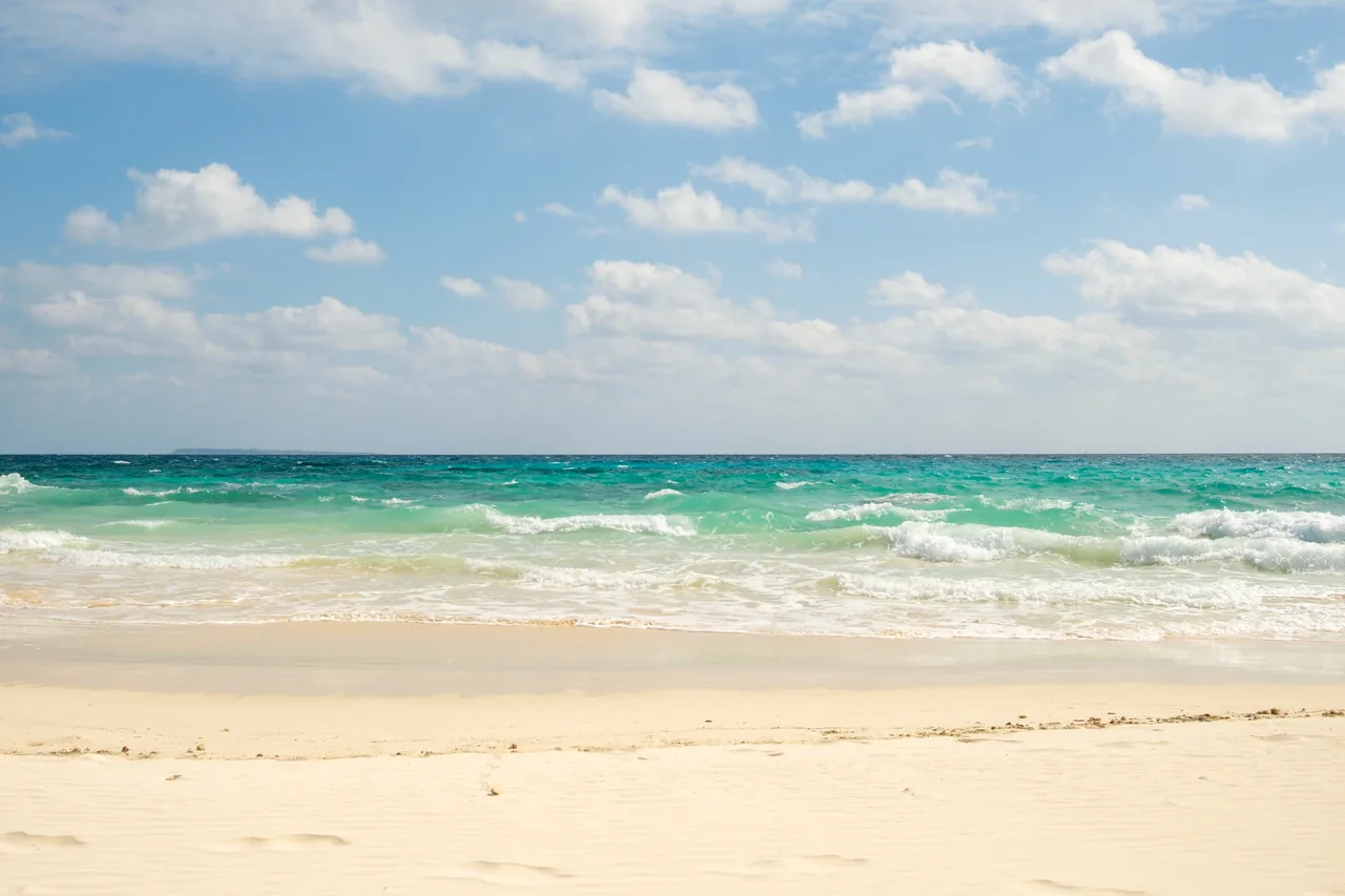 A long stretch of white sand on Irabu island with shallow turquoise water running along it