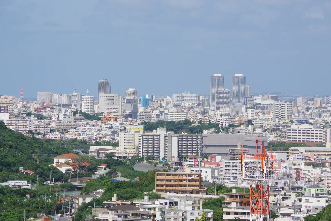 Low rooftops and a few tower blocks spread across Naha, seen from the hill above the city