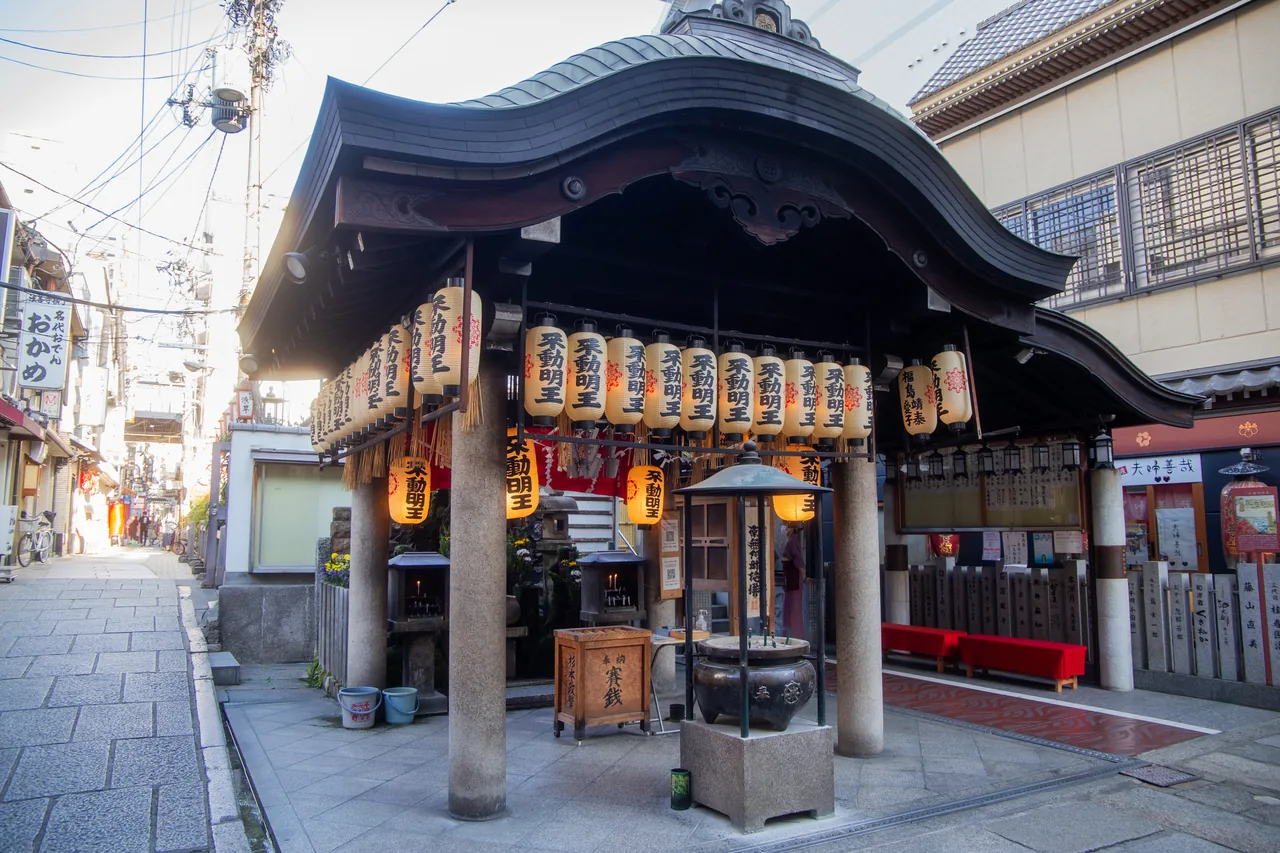 A small temple hall hung with paper lanterns at the end of a narrow stone-paved alley