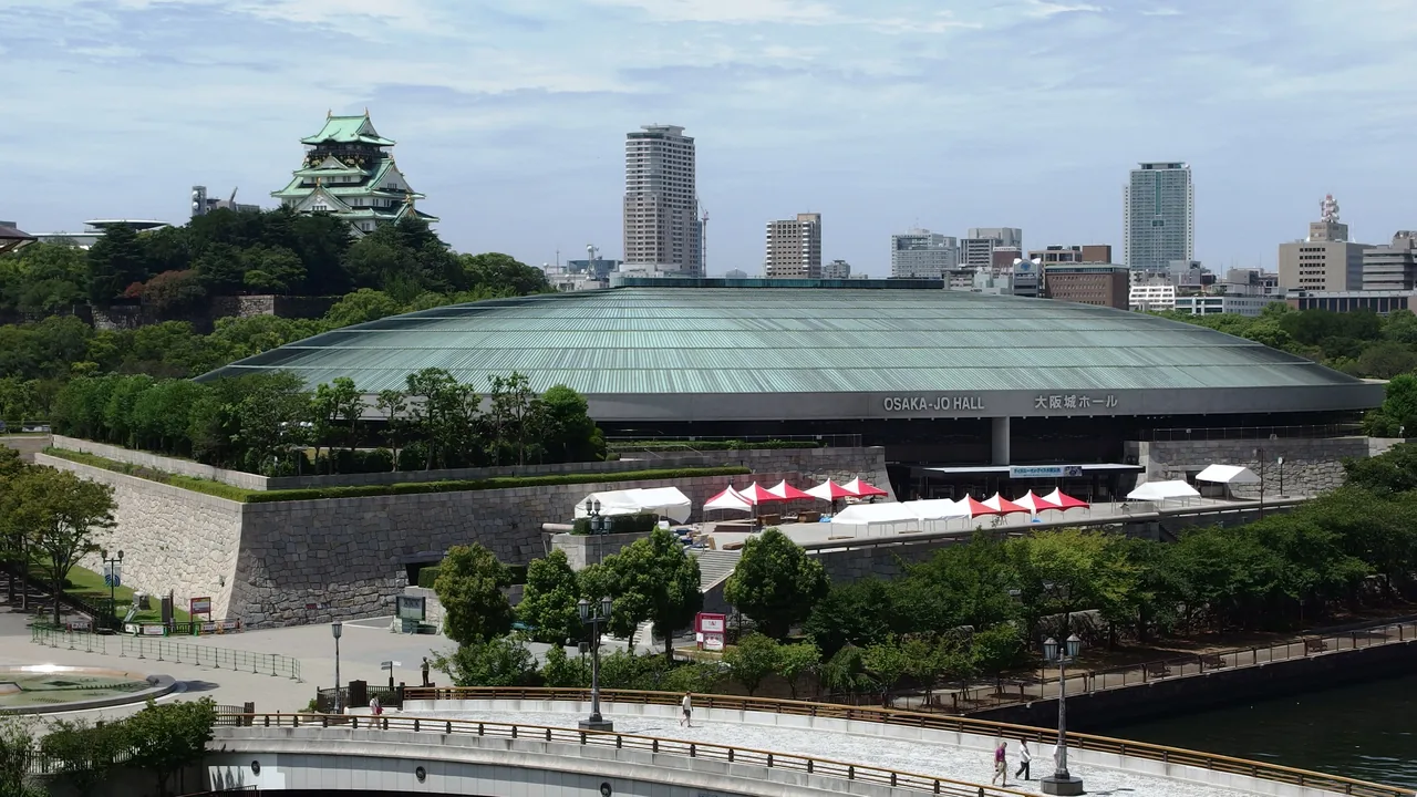 A large arena with a shallow domed roof, with the castle keep visible behind it