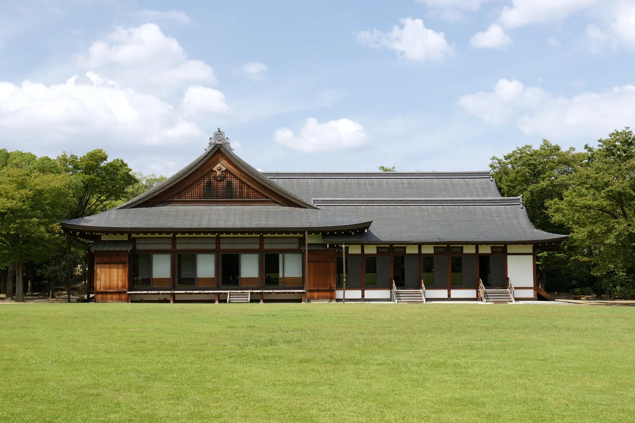 A wide lawn with a low wooden building standing at the far side of it