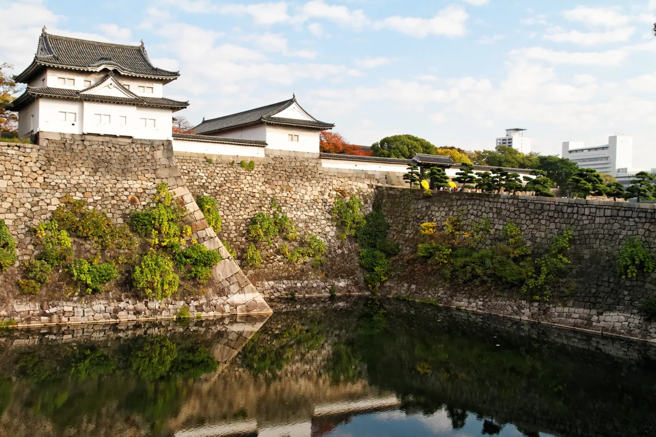 A castle gate and a long white turret seen together across the moat