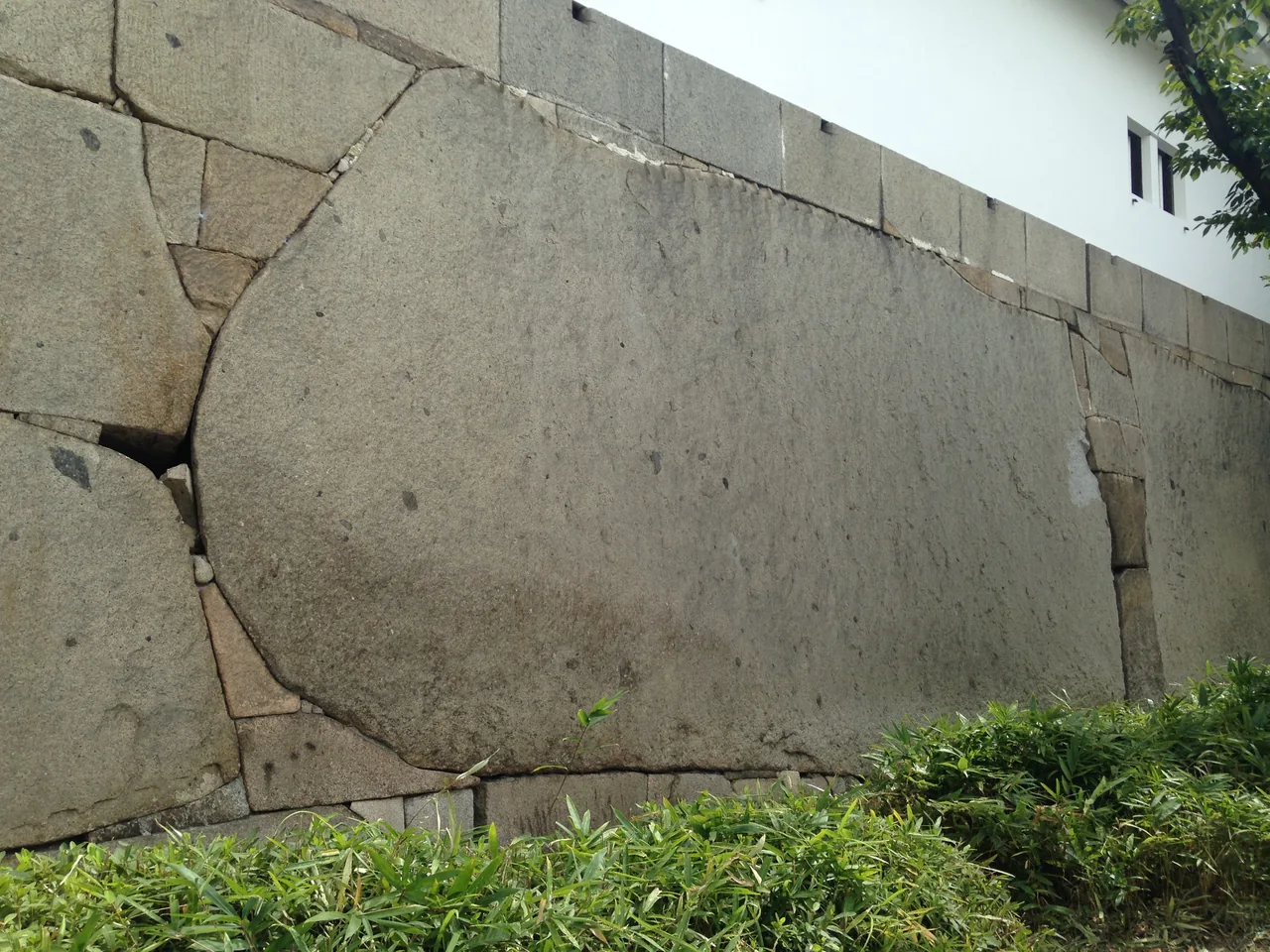 A very large single stone block set into a castle wall beside a path