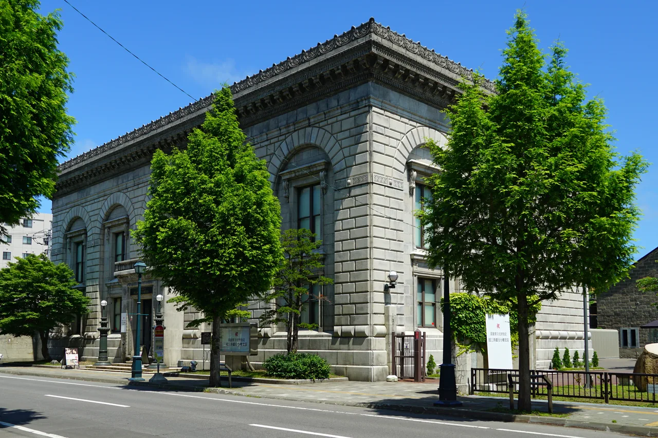 Former bank building with heavy stone columns among trees