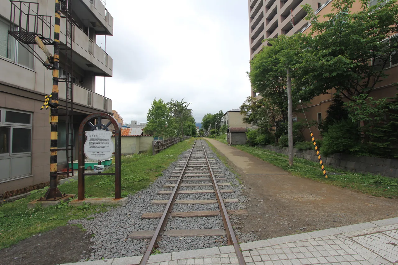 Old railway tracks left in the grass with a footpath beside them