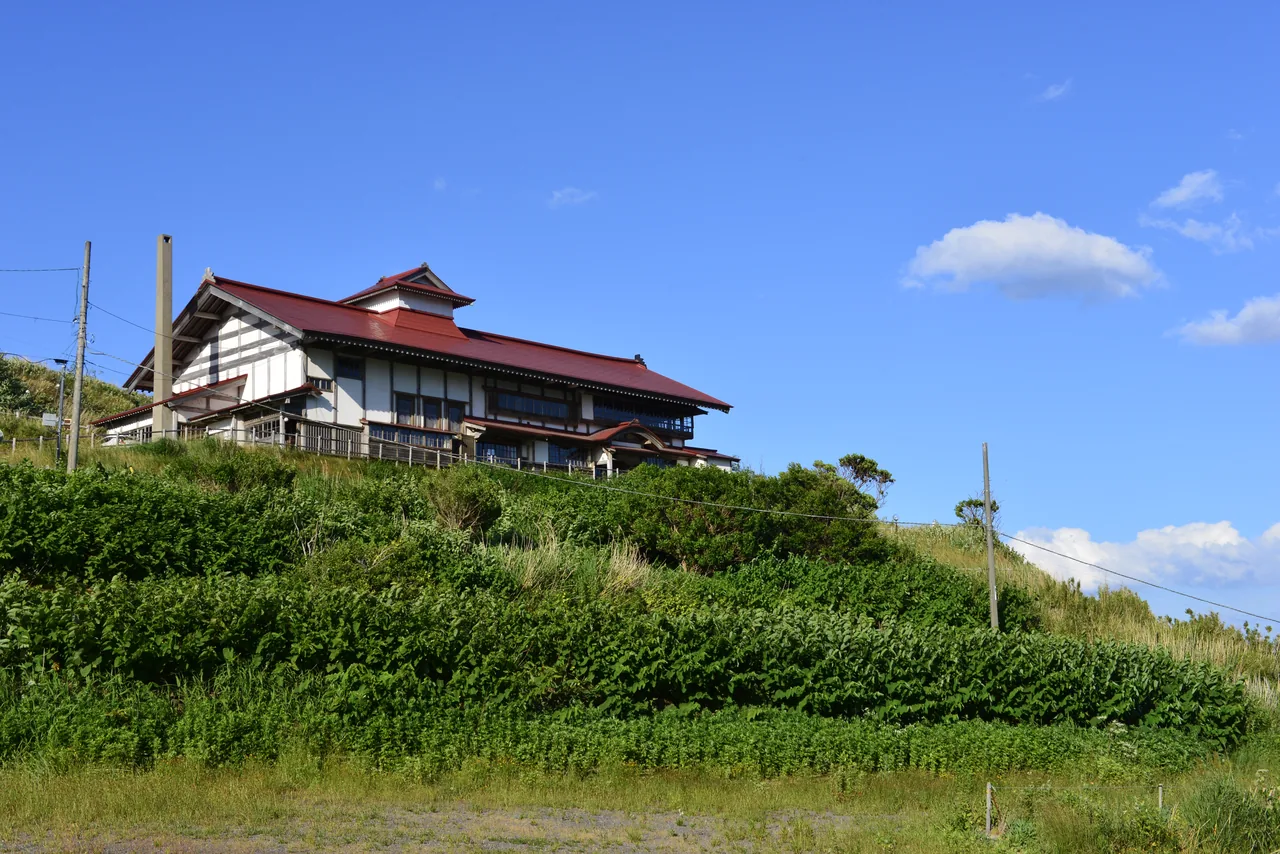 Large red-roofed timber building on a grassy hill