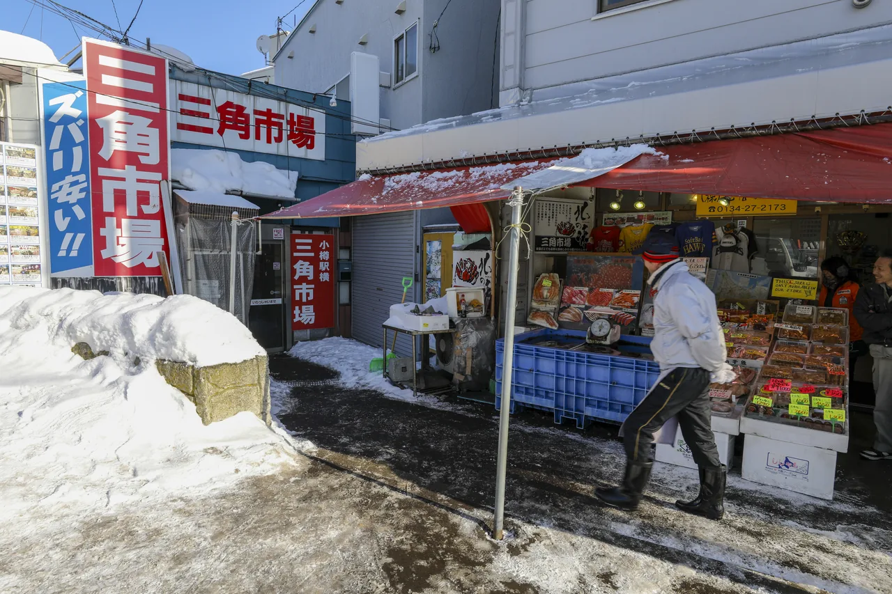 Snowy entrance and sign of Sankaku Market with stalls inside