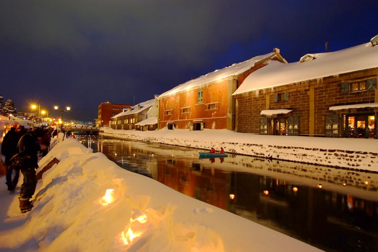 Lanterns floating on the canal at night, candles in the snow along the path and lit warehouses