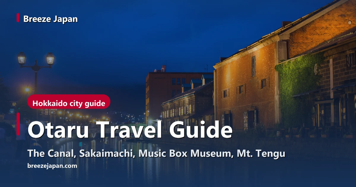 Red-brick and stone warehouses lit at blue hour, their lights reflected in Otaru Canal