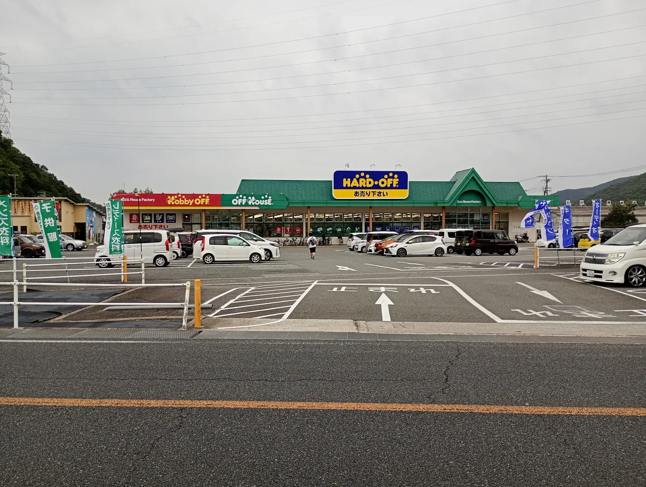 A roadside Hard Off store with Hobby Off and Off House signs on the same building above a car park