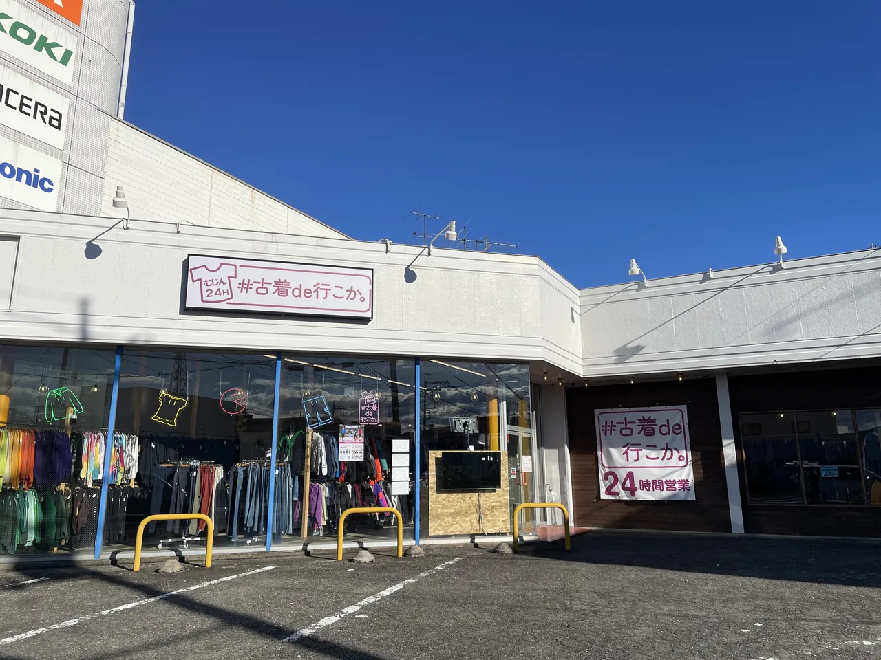 An unstaffed used clothing shop with racks outside and a sign reading open 24 hours