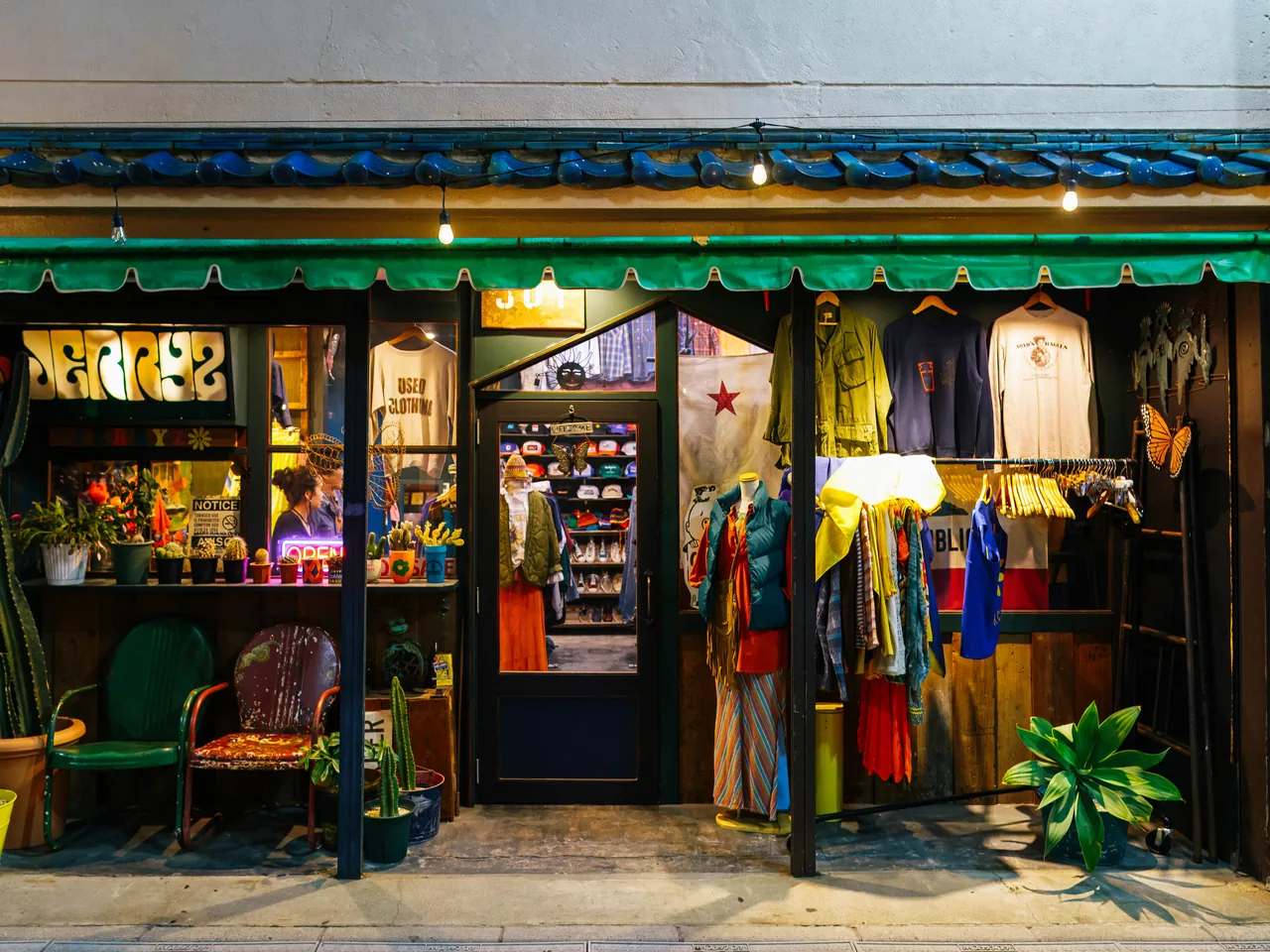 The front of a used clothing shop with a used clothing sign and garments hanging outside