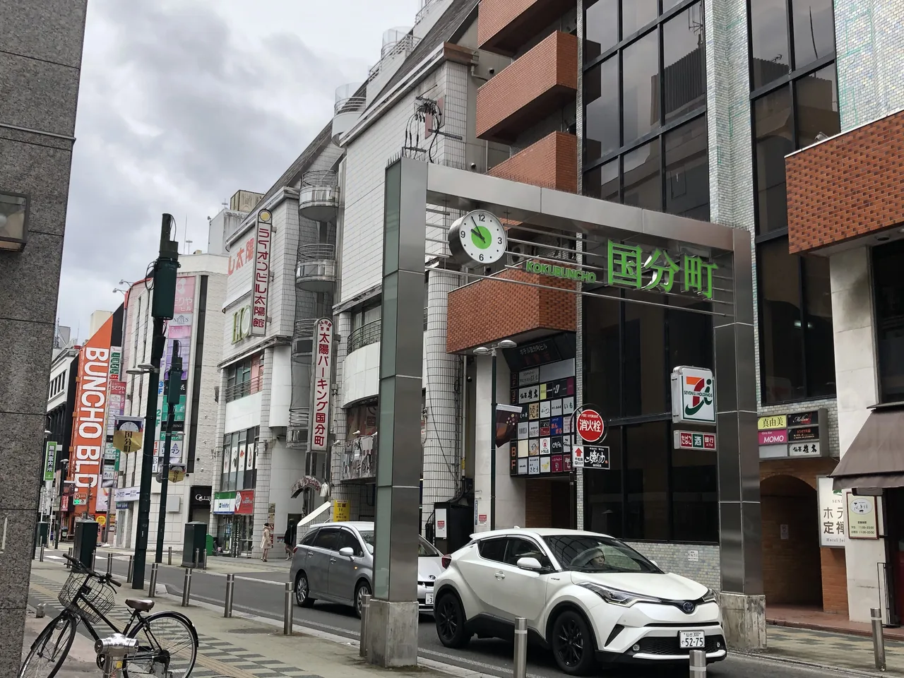 The entrance to Kokubuncho, with a signboard carrying the district name above shopfronts and a street running past