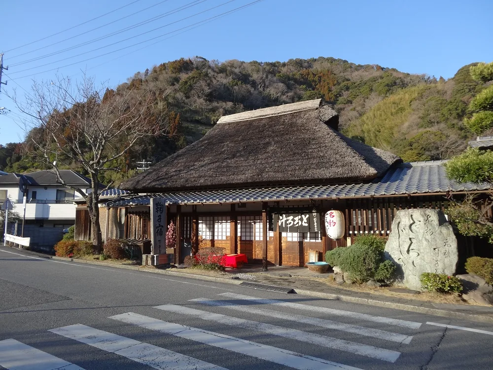 An old dark timber building standing beside the road at Mariko-juku