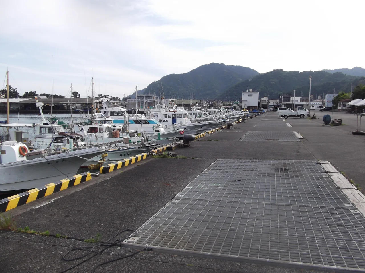 Fishing boats moored along the paved quay at Mochimune harbour