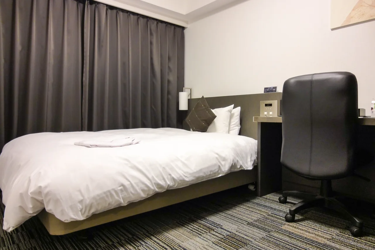 A single room in a Japanese business hotel, with a desk beside the bed A single room in a Japanese business hotel, with a desk beside the bed