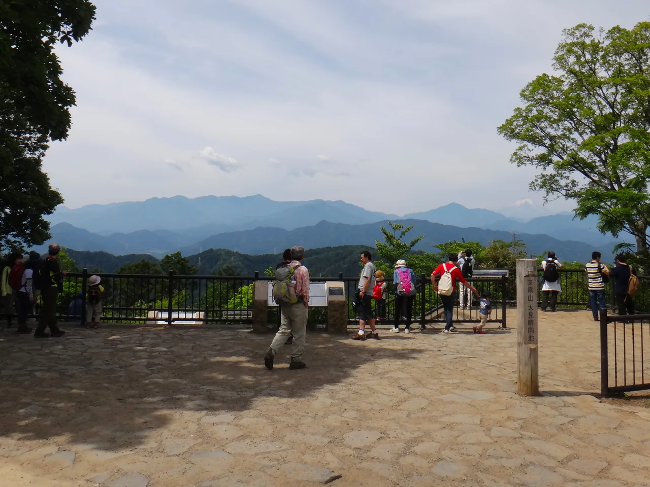 Walkers standing at the open summit of Mt Takao looking out over ridge after ridge of mountains