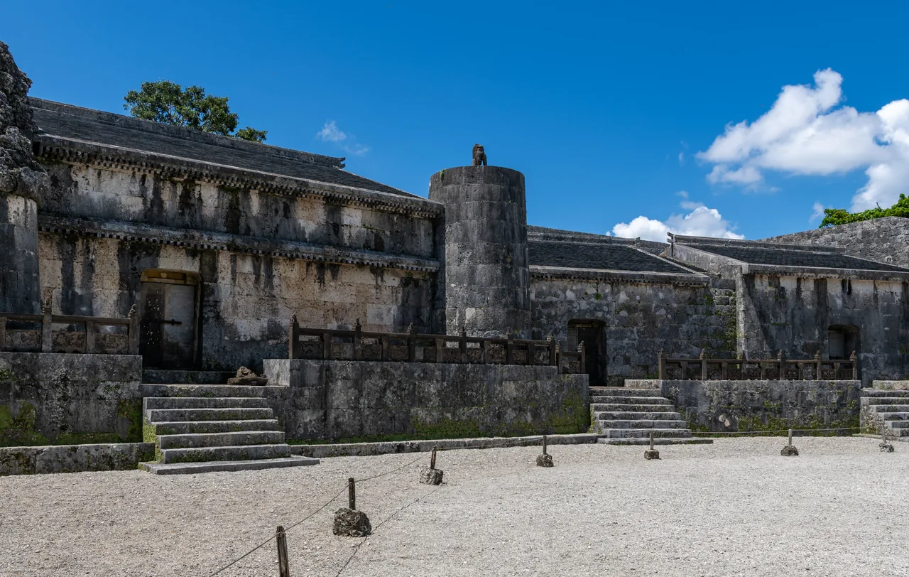 A long stone tomb building behind a walled forecourt of white gravel