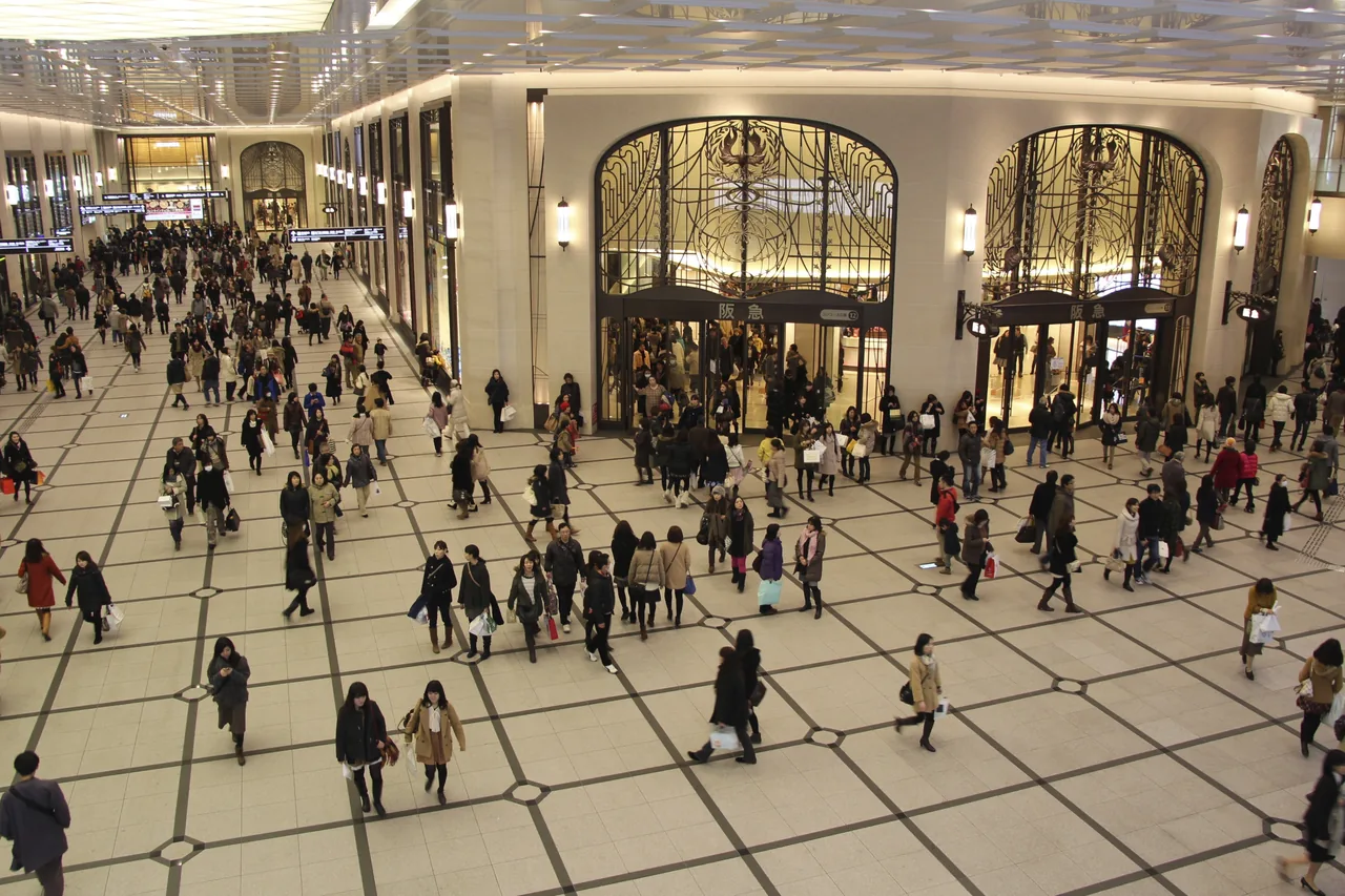 A wide indoor concourse under an arched ceiling with crowds walking through it