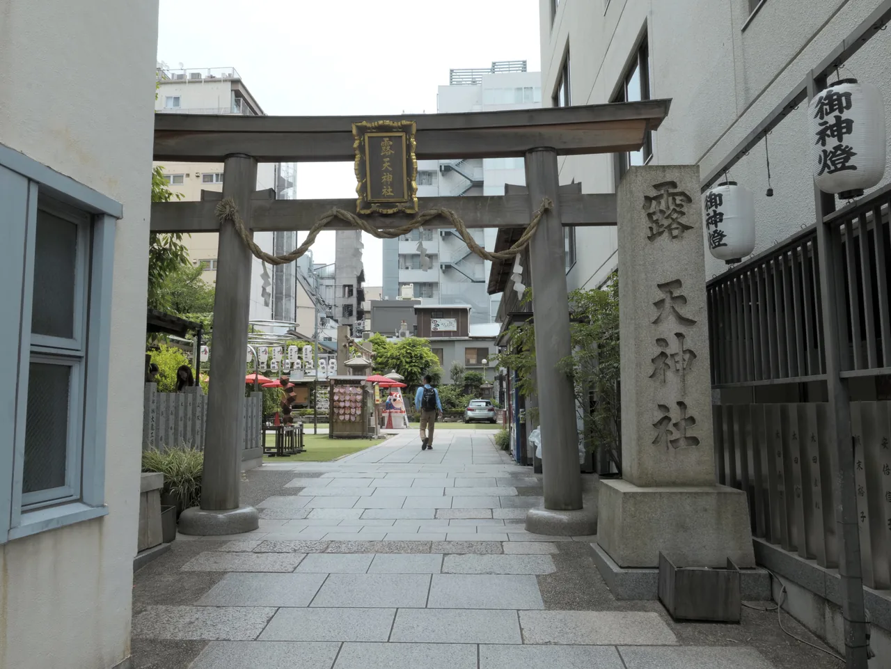 A stone-paved approach to a small shrine hemmed in by buildings on both sides