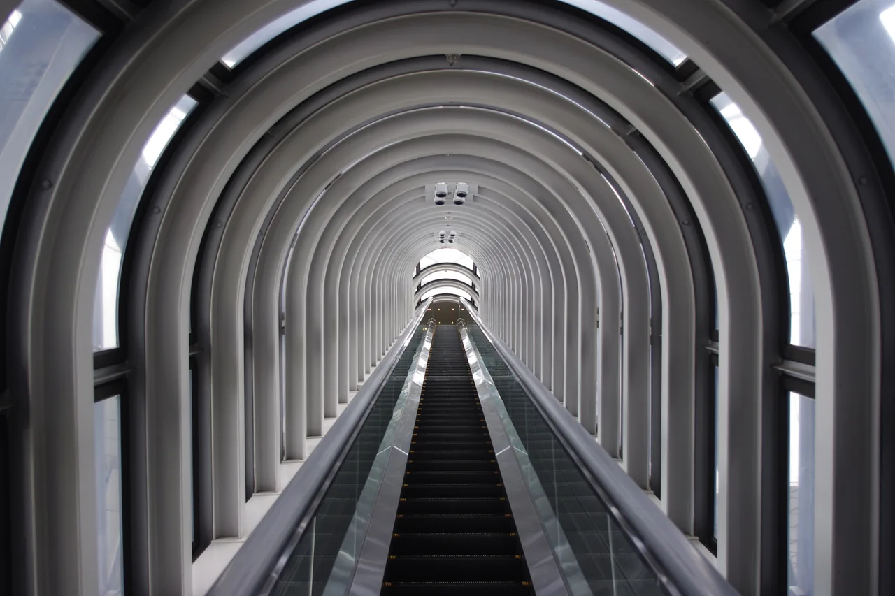 A long escalator running up through an enclosed tunnel inside a building