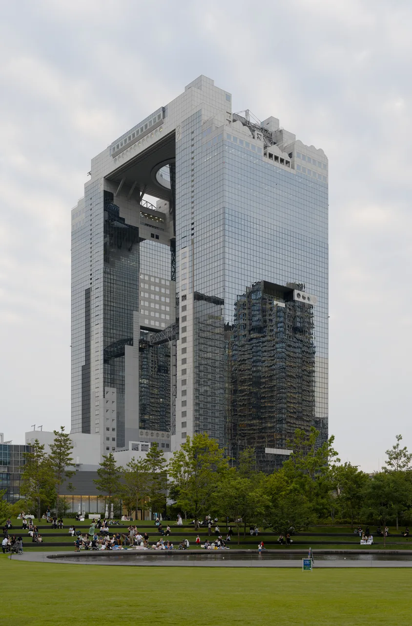 A lawn in a new park with a tall building standing behind it
