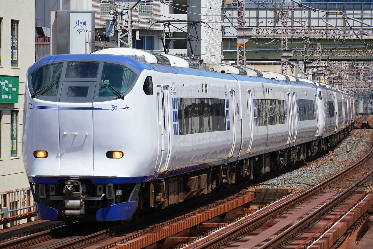 White and blue Haruka limited express train on city tracks