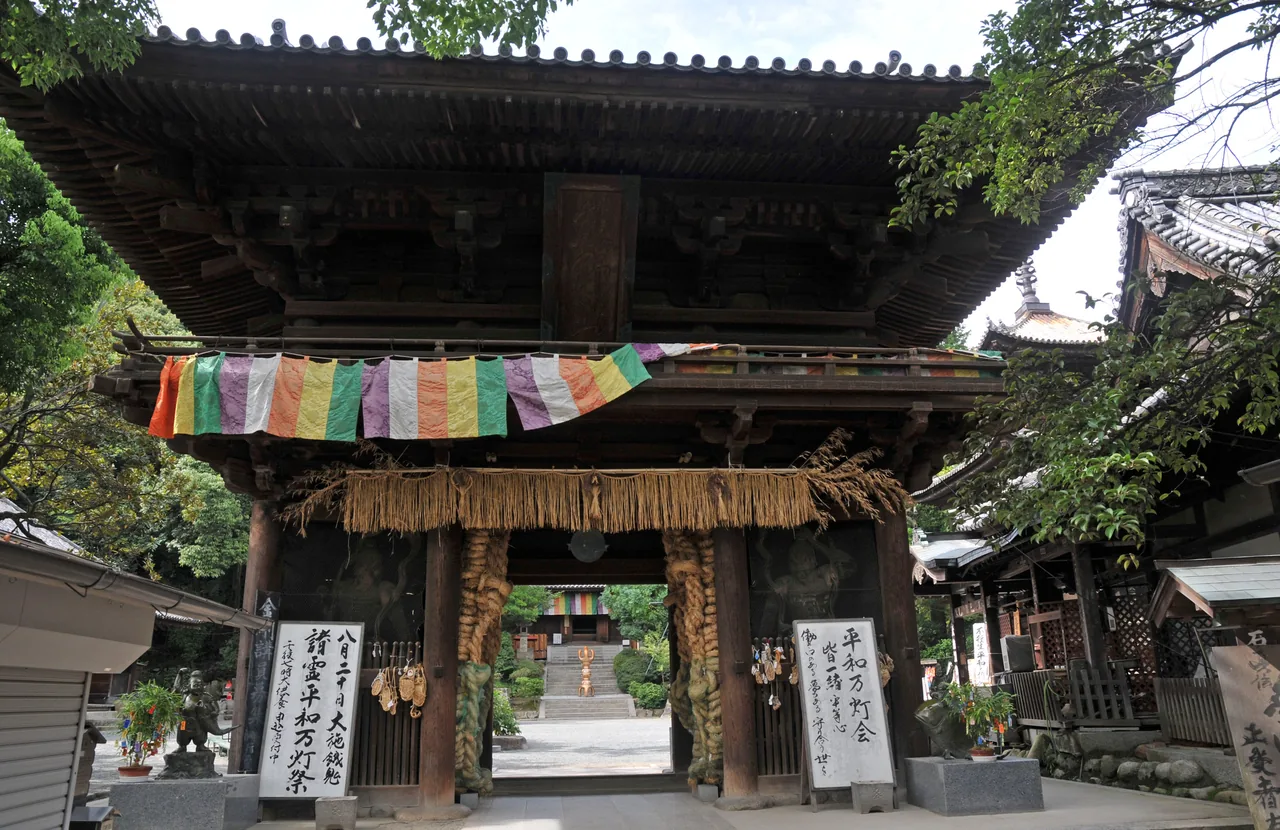 The two-storey wooden Niomon gate of Ishiteji hung with coloured cloth and straw sandals, no people