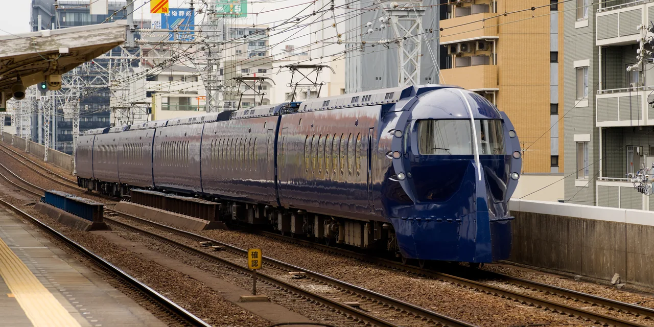 Navy rapi:t train with a rounded nose passing through a city station