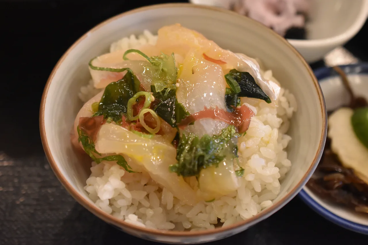 A bowl of white rice topped with raw sea bream, spring onion and nori